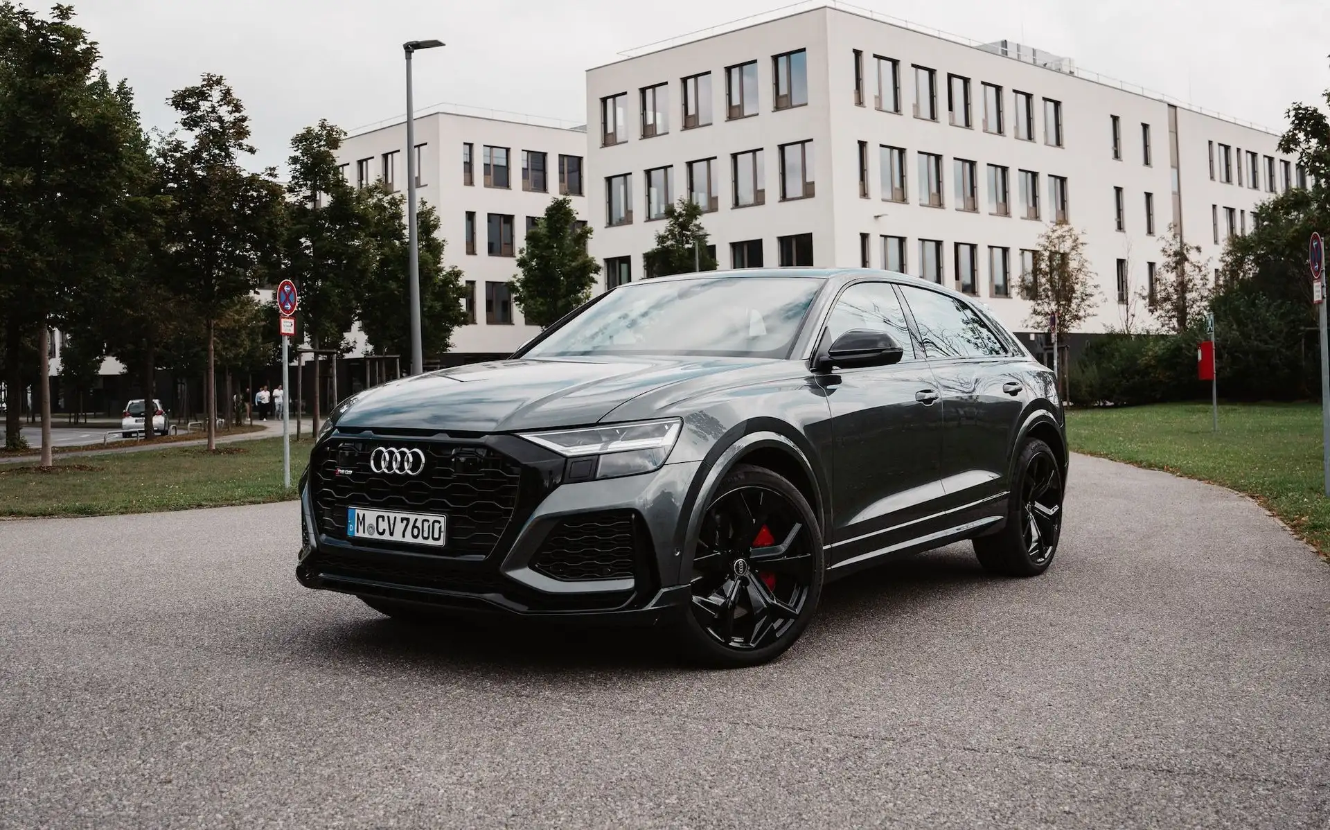 Our grey Audi RS Q8  as seen from the front on a street next to some trees.